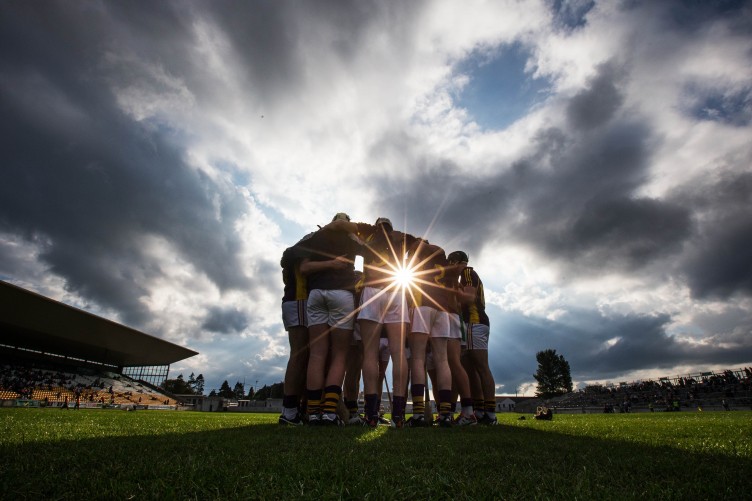 Gaelic football team in a huddle before the match under a dramatic sky