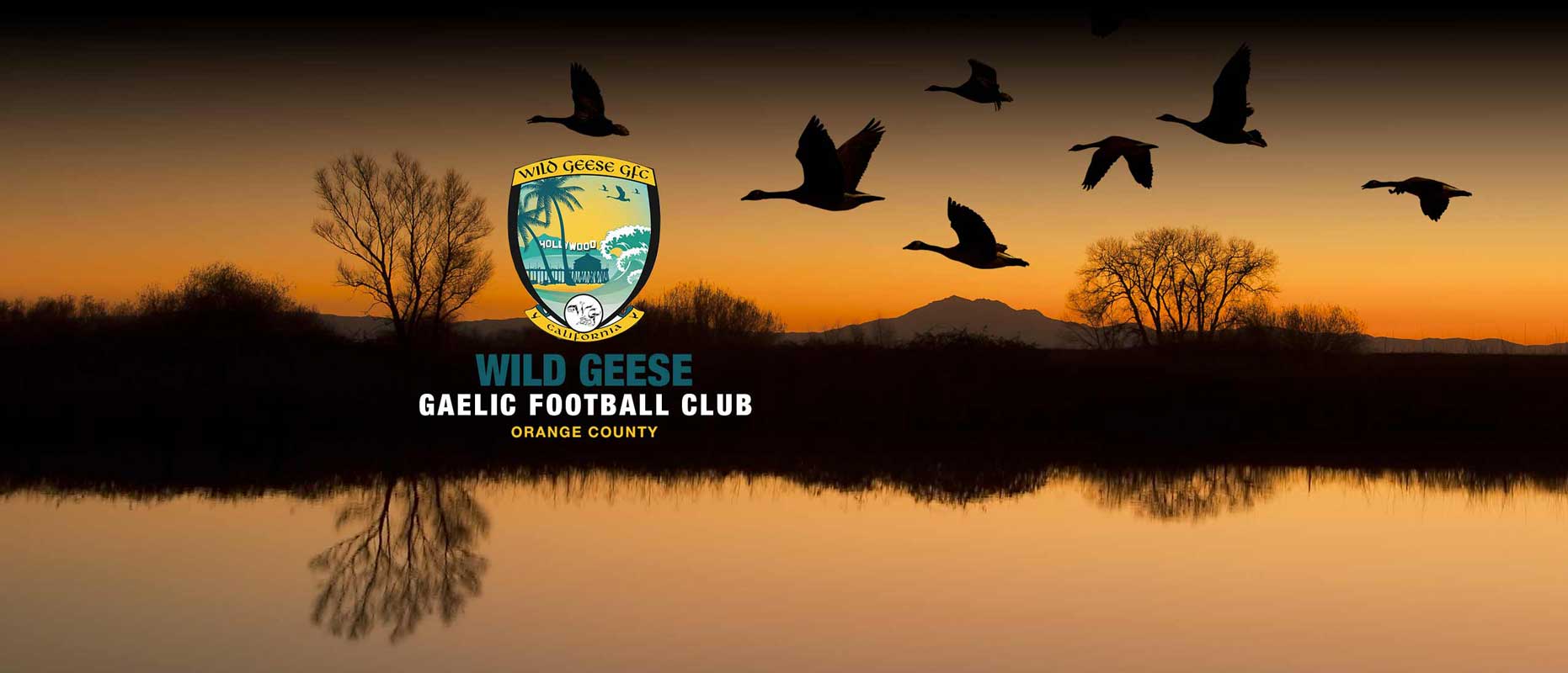 Wild geese flying over a lake at sunset with the Wild Geese Gaelic Football Club crest